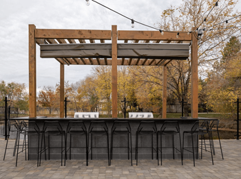 the outdoor bar is under a pergola and has chairs